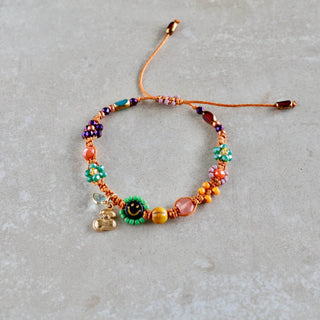 Handgefertigtes Makramee-Armband mit Smiley-Perle, bunten Miyuki-Perlen und kleinen Blumenanhängern in Orange, Grün und Rosa.