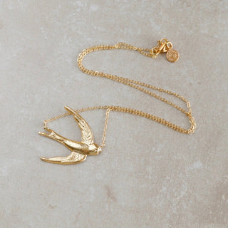 Zarte Gold-Midi-Halskette mit Karabiner-Verschluss, in der Mitte ist eine Schwalbe.